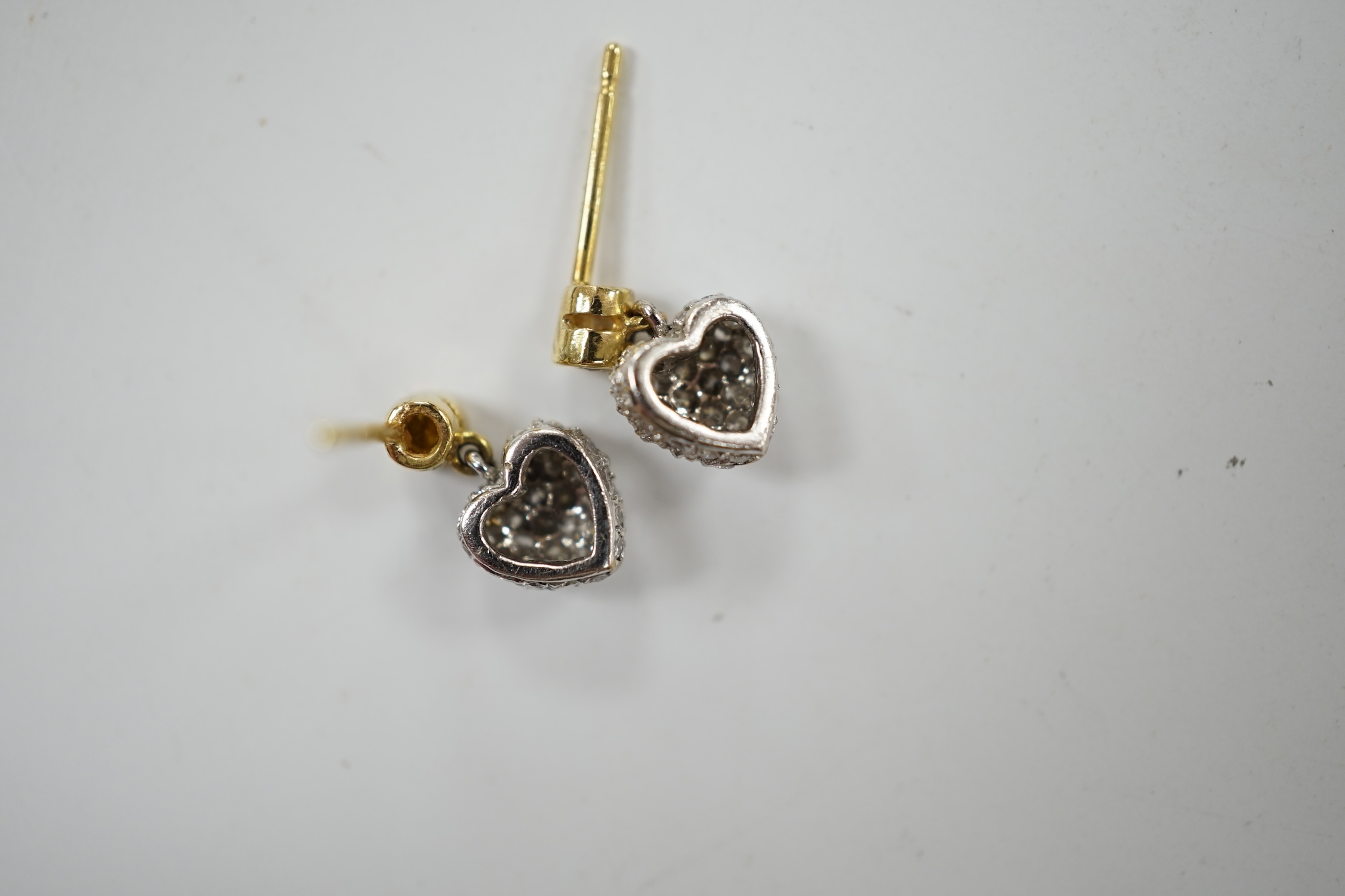 A modern pair of 750 and pave set diamond chip heart shaped ear studs, with single stone yellow diamond set bale, 9mm, gross weight 1.9 grams. Condition - good